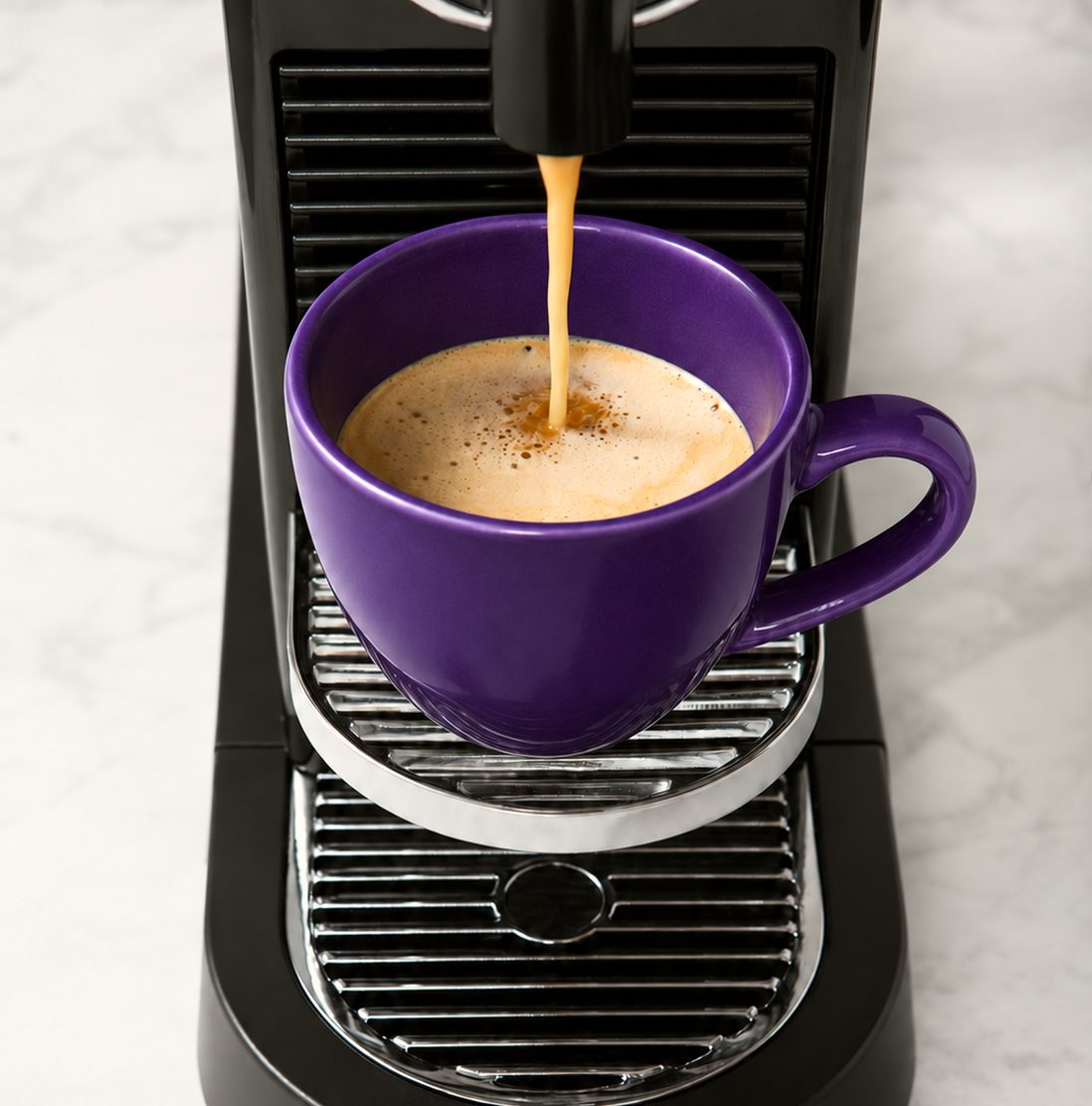 Vue de dessus d'une tasse violette sous la machine, le café qui coule et sa mousse