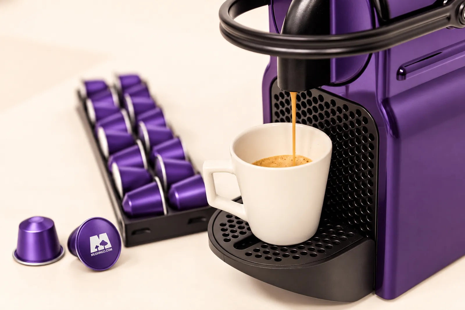 Una máquina de cápsulas morada sirve un café en una taza blanca, junto a cápsulas Mush Caps